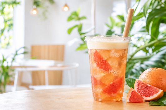 Red grapefruit jasmine iced tea in a clear plastic takeaway cup in a bright UK café