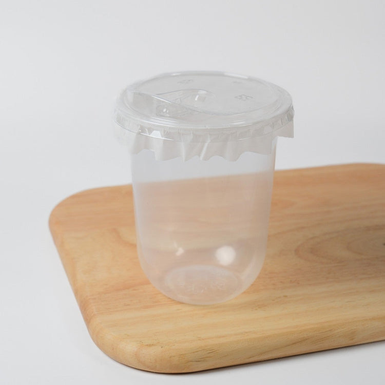 Clear disposable bubble tea cups (95mm) shown with matching flat lids and sealing film for wholesale.