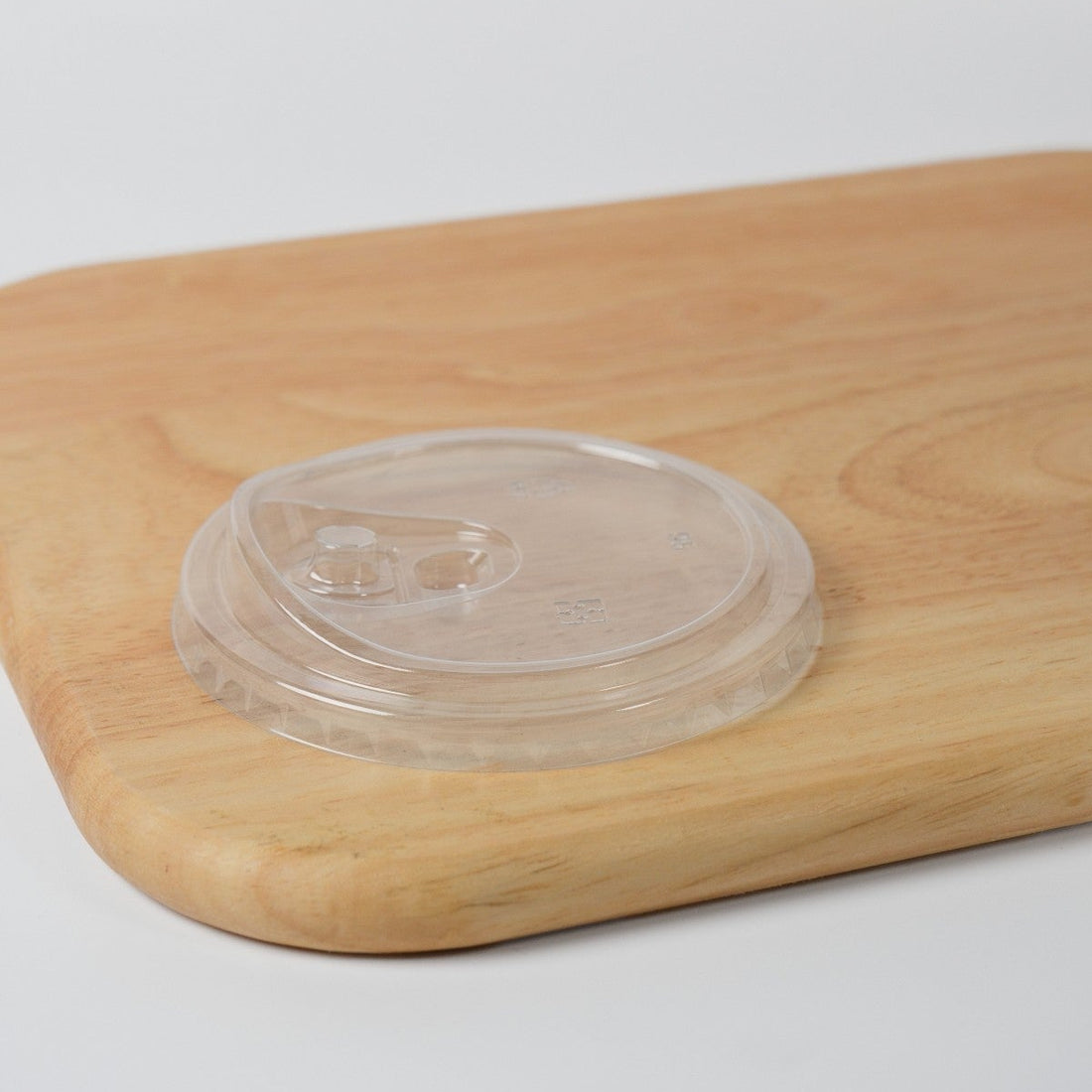Wholesale clear plastic flat sip lid for 90mm bubble tea cups, featuring a direct drinking hole and a removable plug for leak prevention.